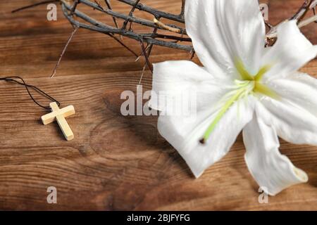 Composizione con croce, giglio e corona di spine su fondo ligneo Foto Stock