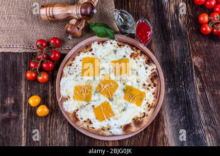 Quattro tipi di formaggio (pizza a quattro formaggi) pizza italiana su un pavimento in legno. Foto Stock