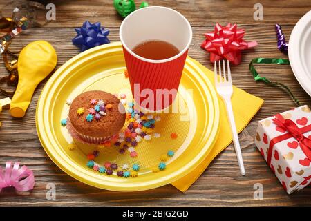 Piatto con cupcake di compleanno e vetro di carta su tavolo di legno Foto Stock