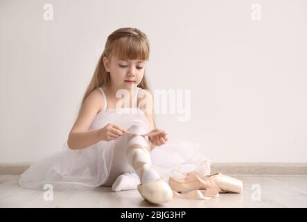 Bella ballerina ballerina che lega scarpe pointe in studio di danza leggera Foto Stock