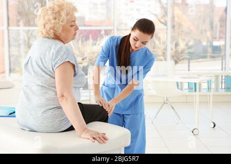 Ortopedist femmina che esamina la donna anziana in clinica Foto Stock