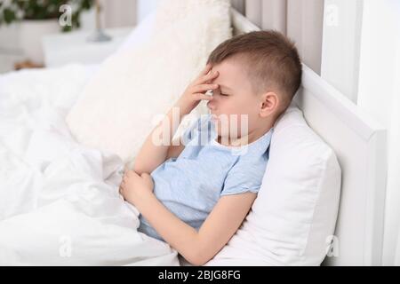 Bambino che soffre di mal di testa mentre si trova a letto a casa Foto Stock