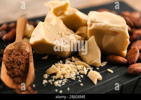 Burro di cacao, polvere e fagioli su legno Foto Stock