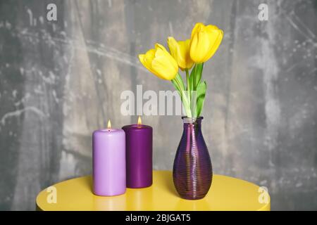 Bouquet di tulipani in vaso e lilla colore candele su tavola Foto Stock