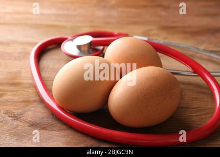 Uova con stetoscopio su tavola di legno Foto Stock