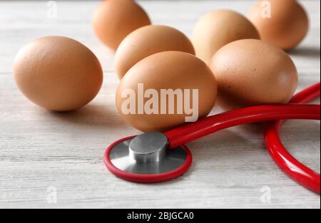 Uova con stetoscopio su tavola di legno Foto Stock