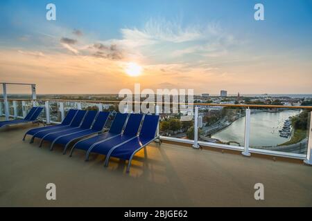 Tramonto con vista sulla città costiera baltica di Warnemunde Rostock Germania dal ponte superiore di una grande nave da crociera nel porto. Foto Stock