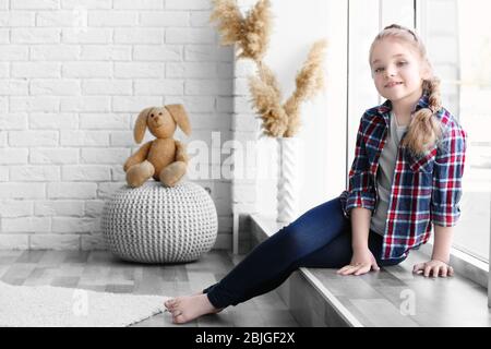 Ragazza sorridente seduta sulla soglia in camera luminosa Foto Stock