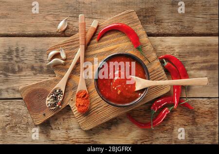 Composizione con gustosa salsa di peperoncino su tavola di legno Foto Stock