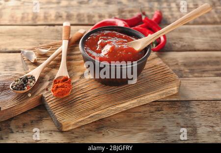 Composizione con gustosa salsa di peperoncino su tavola di legno Foto Stock