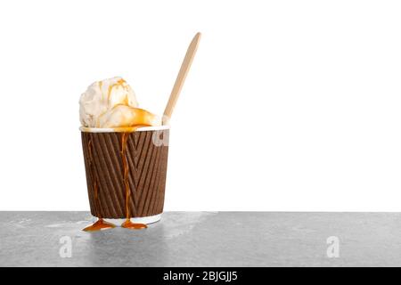 Tazza con gelato alla vaniglia e salsa al caramello sul tavolo Foto Stock