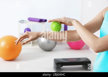 Mani di donna che fa esercizi con palla di gomma in clinica Foto Stock