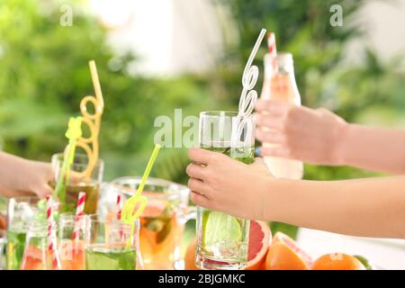 Amici che si rallegrano con bicchieri di diversi tipi di limonata al picnic Foto Stock