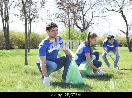 Gruppo di giovani volontari che raccolgono rifiuti nel parco Foto Stock