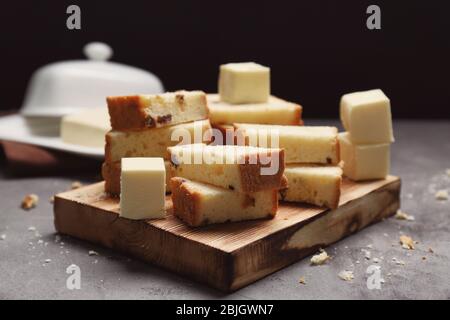 Tagliere con deliziosa torta a fette e cubetti di burro a tavola Foto Stock