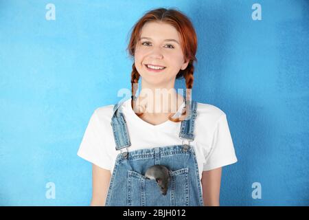 Ragazza adolescente con ratto divertente su sfondo colore Foto Stock