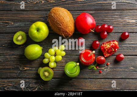 Delizioso succo in bottiglie con ingredienti su sfondo di legno Foto Stock