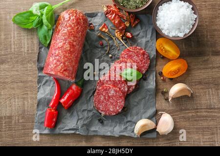 Composizione con salsiccia a fette e peperoncino in tavola Foto Stock
