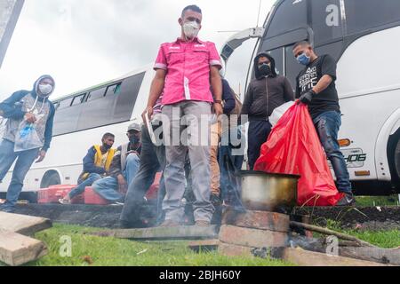 Bogota, Colombia. 29 aprile 2020. Centinaia di migranti venezuelani si sono risparmiati per pagare il viaggio in autobus che li avrebbe ridiretti nel loro paese. Tuttavia, oggi sono detenuti dalle autorità al casello di Los Andes situato sull'autostrada Nord a Bogotà. Credit: Daniel Garzon Herazo/ZUMA Wire/Alamy Live News Foto Stock