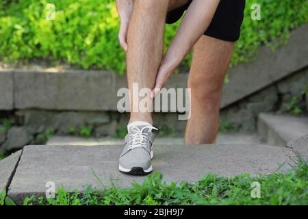 Giovane uomo che soffre di dolore nella gamba all'aperto Foto Stock