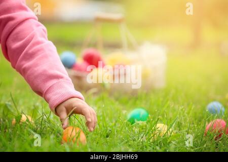 Bambina che raccoglie uova colorate nel parco. Concetto di caccia pasquale Foto Stock