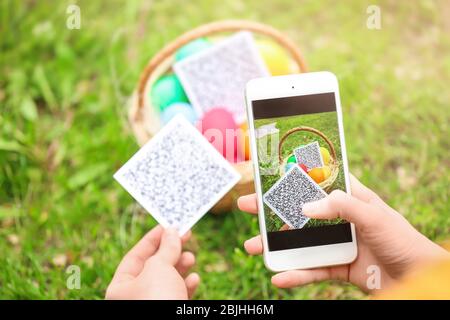 Donna che scansiona il codice QR al parcheggio. Concetto di caccia all'uovo di Pasqua Foto Stock