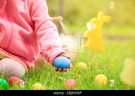 Bambina che raccoglie uova colorate nel parco. Concetto di caccia pasquale Foto Stock