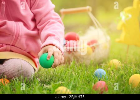 Bambina che raccoglie uova colorate nel parco. Concetto di caccia pasquale Foto Stock