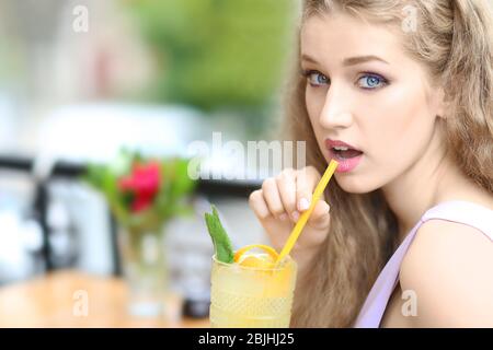 Bella giovane donna bere gustoso succo di frutta in caffè all'aperto Foto Stock