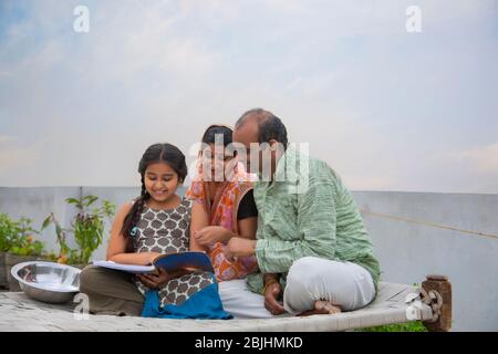 Madre indiana e padre che aiutano le figlie con i compiti Foto Stock