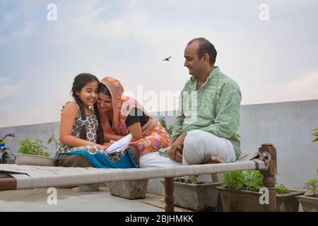 Madre indiana e padre che aiutano le figlie con i compiti Foto Stock