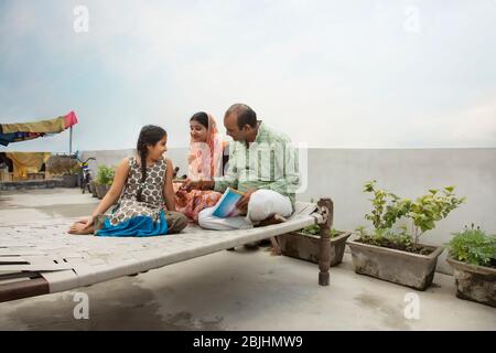 Madre indiana e padre che aiutano le figlie con i compiti Foto Stock