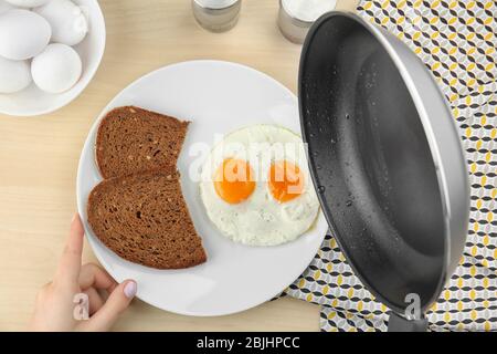 Donna che mette sopra le uova fritte facili sul piatto con il pane Foto Stock