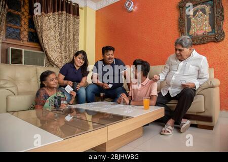 Buona famiglia che gioca con le carte nel soggiorno a casa. Foto Stock