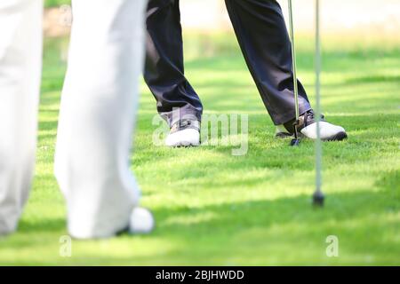 Gambe di giovani uomini che giocano a golf sul campo in giornata di sole Foto Stock