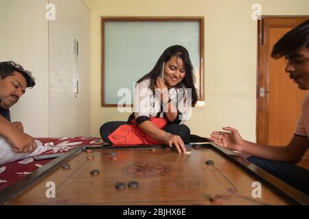 Figlio che gioca a carrom-board con i genitori a casa. Foto Stock