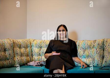 Ritratto di una donna seduta comodamente su un divano. Foto Stock