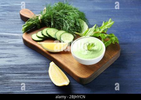 Deliziosa salsa di yogurt in ciotola con ingredienti sul tagliere Foto Stock