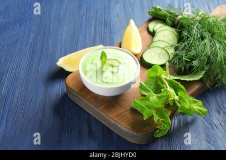 Deliziosa salsa di yogurt in ciotola con ingredienti sul tagliere Foto Stock