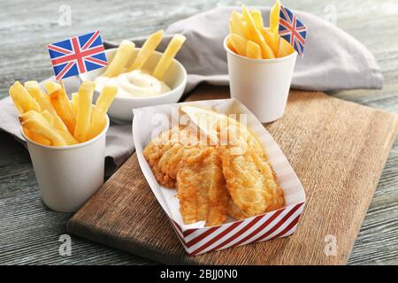 Gustosi patatine fritte di pesce e patatine su tavola di legno Foto Stock