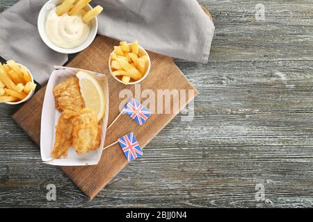 Gustosi patatine fritte di pesce e patatine su tavola di legno Foto Stock