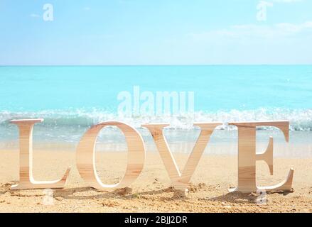 Parola AMORE composto di lettere di legno sul mare. Concetto di matrimonio in spiaggia Foto Stock