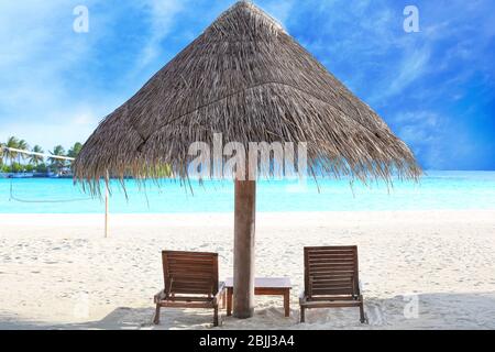 Lettini e ombrellone sulla spiaggia del resort Foto Stock
