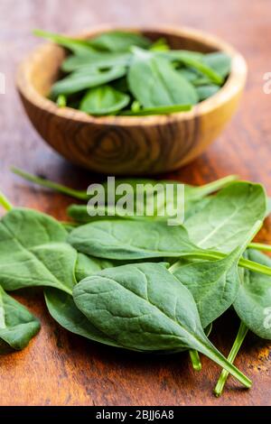 Foglie di spinaci del bambino. Spinaci verdi su tavola di legno. Foto Stock