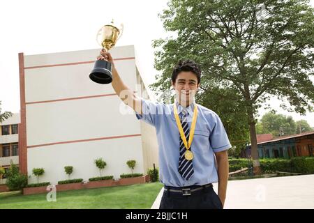 Studente che tiene un trofeo trionfalmente Foto Stock