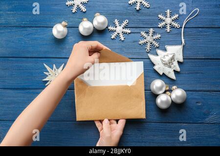 Donna che mette lettera di Natale in busta a tavola di legno Foto Stock