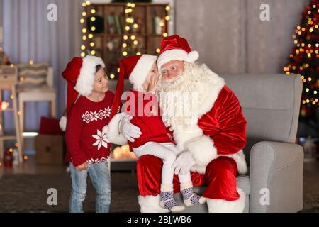 I bambini che raccontano a Santa i loro desideri in camera con belle decorazioni natalizie Foto Stock