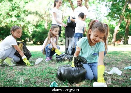 Giovani volontari e bambini che raccolgono rifiuti nel parco Foto Stock