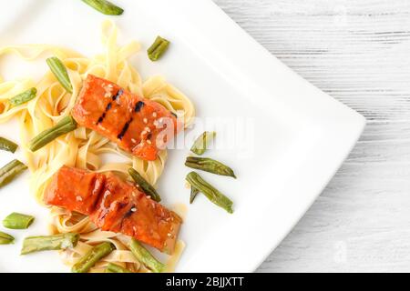 Piatto con pesce, pasta e fagioli verdi gustosi a tavola Foto Stock