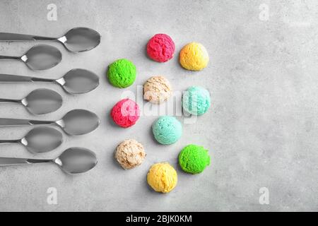 Composizione con scoop colorati di gelato e cucchiai su sfondo chiaro Foto Stock